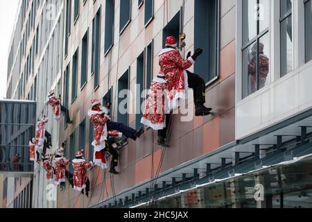 Mosca, Russia. 24th Dic 2021. Gli operatori di emergenza russi vestiti come Moroz di D scalano il muro di un ospedale per bambini mentre salutano i bambini per il prossimo anno nuovo a Mosca, Russia, il 24 dicembre 2021. Credit: Alexander Zemlianichenko Jr/Xinhua/Alamy Live News Foto Stock