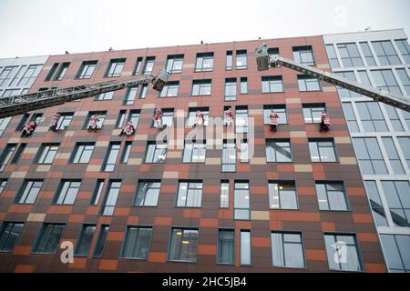 Mosca, Russia. 24th Dic 2021. Gli operatori di emergenza russi vestiti come Moroz di D scalano il muro di un ospedale per bambini mentre salutano i bambini per il prossimo anno nuovo a Mosca, Russia, il 24 dicembre 2021. Credit: Alexander Zemlianichenko Jr/Xinhua/Alamy Live News Foto Stock