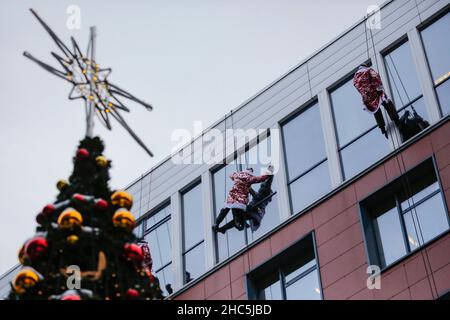 Mosca, Russia. 24th Dic 2021. Gli operatori di emergenza russi vestiti come Moroz di D scalano il muro di un ospedale per bambini mentre salutano i bambini per il prossimo anno nuovo a Mosca, Russia, il 24 dicembre 2021. Credit: Alexander Zemlianichenko Jr/Xinhua/Alamy Live News Foto Stock