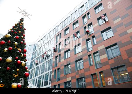 Mosca, Russia. 24th Dic 2021. Gli operatori di emergenza russi vestiti come Moroz di D scalano il muro di un ospedale per bambini mentre salutano i bambini per il prossimo anno nuovo a Mosca, Russia, il 24 dicembre 2021. Credit: Alexander Zemlianichenko Jr/Xinhua/Alamy Live News Foto Stock