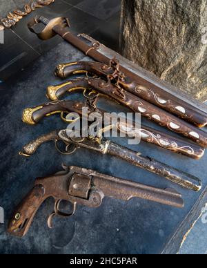 Arrugginite vecchie armi, tra cui un revolver, pistole a polvere e spada disposte per la vendita ai turisti, a causa della più alta connessione militare al servizio di guerra Foto Stock