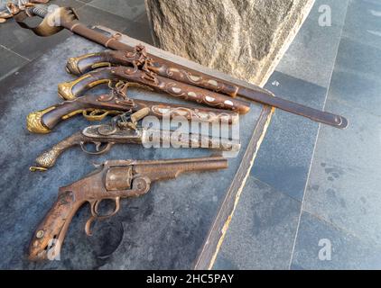 Arrugginite vecchie armi, tra cui un revolver, pistole a polvere e spada disposte per la vendita ai turisti, a causa della più alta connessione militare al servizio di guerra Foto Stock