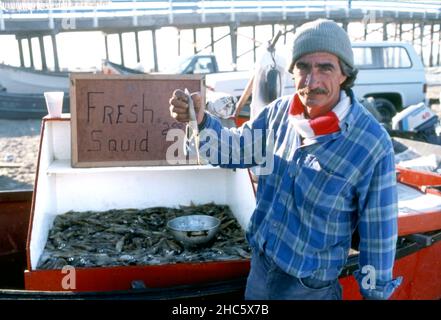 Pescatore che vende calamari freschi catturati presso lo storico mercato della flotta di pesca Dory a Newport Beach, California Foto Stock