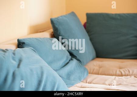 Comodo divano vicino alla parete pieno di cuscini verdi Foto Stock