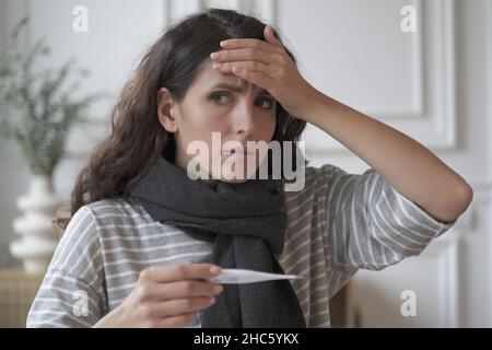 Triste malato giovane italiana donna che indossa sciarpa a maglia intorno al collo che soffre di influenza freddo in casa Foto Stock