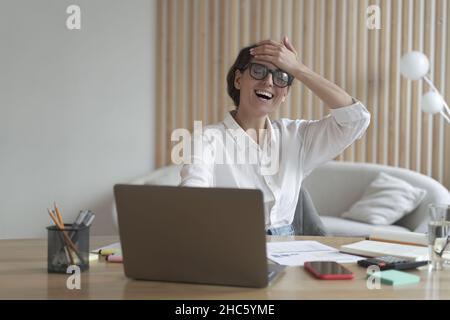 Felice e allegra giovane donna d'affari italiana che riceve un'offerta di lavoro via e-mail sul portatile Foto Stock