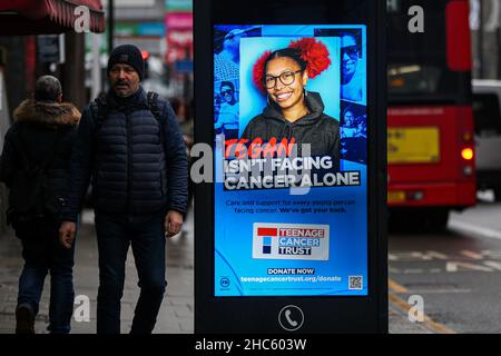 Londra, Regno Unito. 24th Dic 2021. Un uomo passa davanti ad un annuncio digitale Teenage Cancer Trust. Credit: SOPA Images Limited/Alamy Live News Foto Stock