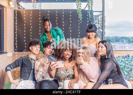 Amici multietnici che prendono un selfie su una terrazza Foto Stock