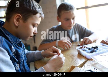 Ritratto di amici che fanno braccialetti in officina Foto Stock