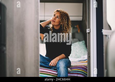 Bella signora sedersi in camera da letto sul camping auto camper interno furgone. Concetto di viaggio femminile e stile di vita nomade alternativo. Lady enjoii Foto Stock