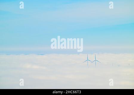 Due mulini a vento in dense nuvole contro un cielo nuvoloso Foto Stock