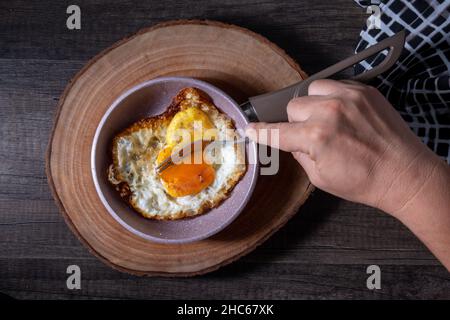 le uova, sempre nella padella, sono riposte su un tagliere di legno Foto Stock