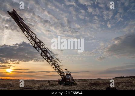 Bel colpo di una gru che lavora sotto il cielo nuvoloso durante l'alba Foto Stock