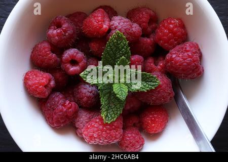 Vista dall'alto di un mazzo di fragole rosse fresche in una ciotola di ceramica su una superficie di legno scuro Foto Stock