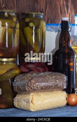 Vari tipi di legumi e cereali in sacchi di plastica sulla mensola. Bevande in vasetti di vetro, stoccaggio di cibo. Crisi, carestia, aumento dei prezzi Foto Stock