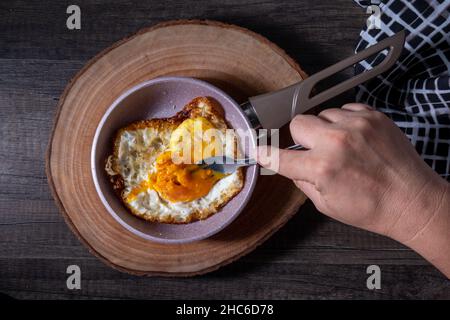 le uova, sempre nella padella, sono riposte su un tagliere di legno Foto Stock
