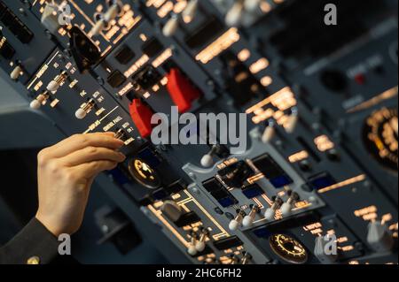 Primo piano della mano di un pilota che gira un interruttore a levetta sul pannello di controllo. Foto Stock