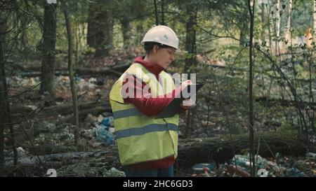 Ecologista donna in abbigliamento da lavoro problemi multa per lo scarico di rifiuti di plastica in parco Foto Stock