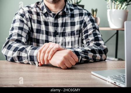 Un uomo che soffre di dolore articolare in mano e polso, artrite reumatoide e malattie professionali Foto Stock