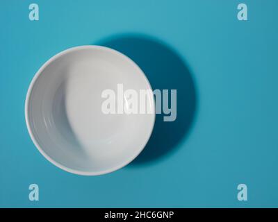 ciotola bianca vuota su sfondo blu. stile minimalista. Foto Stock