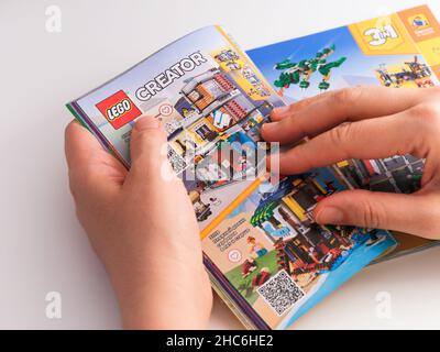 Tambov, Federazione russa - 21 dicembre 2021 Woman browsing Catalogo Lego su una pagina con set Lego Creator. Foto Stock