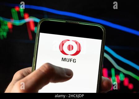 In questa foto raffigurante il logo della più grande banca giapponese Mitsubishi UFJ Financial Group MUFG Bank visto su uno smartphone con un grafico dell'indice di borsa economica sullo sfondo. Foto Stock