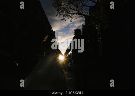 Crop sposa e sposo tenere le mani e camminare sulla strada Foto Stock