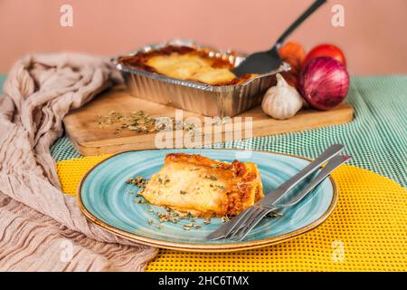 Una porzione di lasagna appena fatta con bolognese pronto da mangiare servita su un piatto con posate. Foto Stock