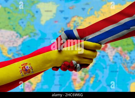 Handshake tra Spagna e norvegia bandiere dipinte su hands.with sfondo della mappa del mondo Foto Stock