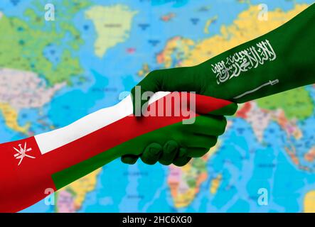 Handshake tra Arabia Saudita e Oman bandiere dipinte su hands.with sfondo della mappa del mondo Foto Stock