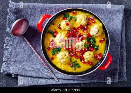 Ash-e Anar, zuppa di Pomegranate di Pea spaccata persiana con polpette di agnello in una pentola rossa su un tavolo di cemento, vista orizzontale dall'alto, giacitura piatta, primo piano Foto Stock