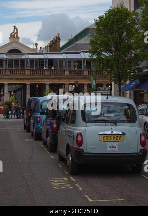 Fila di quattro taxi di Londra sulla strada in attesa di passeggeri Foto Stock