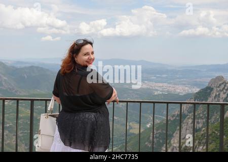 Plump donna adulta medio sullo sfondo panoramico della valle del fiume Llobregat da Montserrat Abbey verso Serra de Collcardus, Catalogna, Spagna. Foto Stock