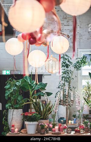 Scatto verticale di decorazioni di partito con piante, fiori e candele accese su un tavolo Foto Stock