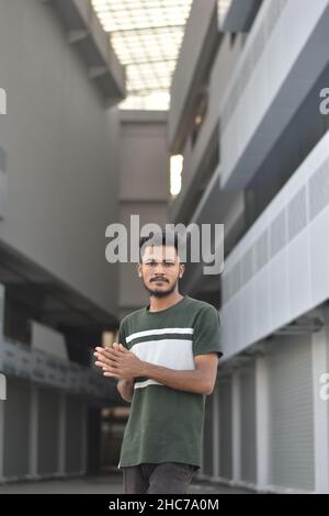 Scatto inclinato di un giovane indiano con camicia verde scuro in posa per la macchina fotografica Foto Stock