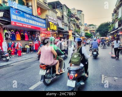 La strada trafficata con la gente che guida le motociclette in Hanoi, Vietnam Foto Stock