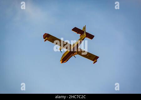 Inquadratura a basso angolo del Canadair Fire Fight Airplane che vola contro il cielo blu Foto Stock