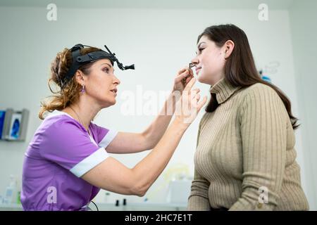 Dottore professionale di otorhinolaringologist che fa esame del naso con otoscopio in ospedale moderno. Congestione nasale, sinusite, allergia concetto Foto Stock