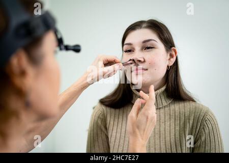 Dottore professionale di otorhinolaringologist che fa esame del naso con otoscopio in ospedale moderno. Congestione nasale, sinusite, allergia concetto Foto Stock