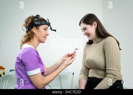 Dottore professionale di otorhinolaringologist che fa esame del naso con otoscopio in ospedale moderno. Congestione nasale, sinusite, allergia concetto Foto Stock