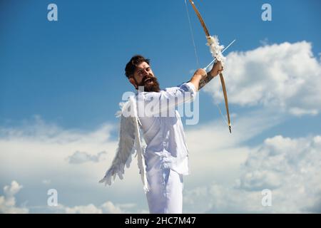 San Valentino concetto. Divertente angelo Cupido puntando con arco e freccia su uno sfondo cielo in cielo. Concetto comico dell'umorismo. Foto Stock