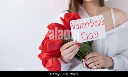 Donna che tiene un bouquet di bei tulipani rossi su sfondo bianco, Card con l'iscrizione San Valentino. Foto Stock
