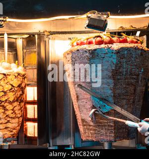 Donatrice Kebab. Chef che taglia famoso cibo turco Street food Pollo e ciambelle di carne. Foto Stock