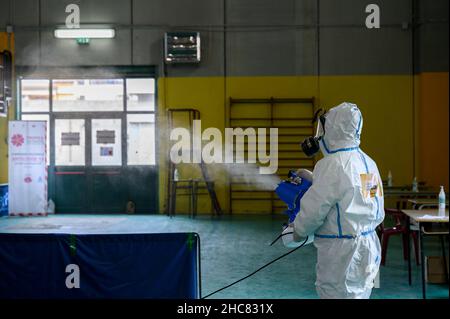 Un operatore sanitario che indossa i dispositivi di protezione individuale (PPE) visto disinfettare la zona, durante la vaccinazione. La campagna anti-Covid19 vaccino nella città turistica di Tropea, sulla Costa degli dei (Costa degli dei) in Calabria (Italia) continua anche a Natale con una giornata aperta nella Sala della palestra comunale. Con l'aumento della paura per la variante Omicron, i giorni di apertura per le festività natalizie e di Capodanno sono stati eliminati dall'Azienda sanitaria Provinciale di Vibo Valentia, con l'aiuto della protezione civile locale (protezione civile). (Foto di Valeria Ferrar Foto Stock