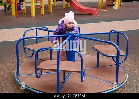 bambino su un carosello sul parco giochi. Foto Stock