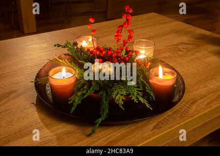 Decorazioni natalizie fatte a mano con candele, rami di conifere e bacche rosse Foto Stock