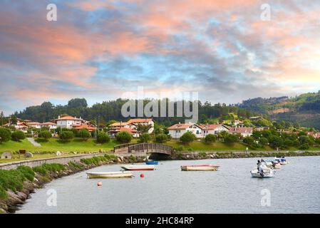 Zona residenziale con chalet, ponte pedonale in legno e piccole barche da diporto con spettacolare cielo all'alba, Plencia, Biscay, Paesi Baschi, Spa Foto Stock