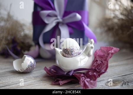 Composizione pasquale con un uovo e un regalo su sfondo sfocato. Foto Stock