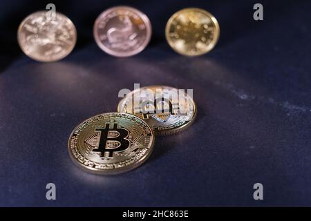 Una moneta di bitcoin d'oro si trova davanti ad una moneta di Krugerrand e ad un dollaro d'oro e ad una foglia d'acero canadese Foto Stock