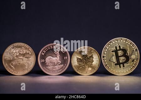 La moneta di bitcoin d'oro si trova accanto ad una moneta di Krugerrand e ad una moneta di oro e di acero canadese Foto Stock